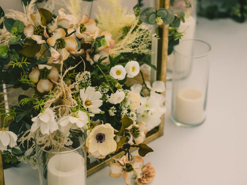 White blooms and greenery arranged beside glass pillar candles on a table, Clearwater, FL