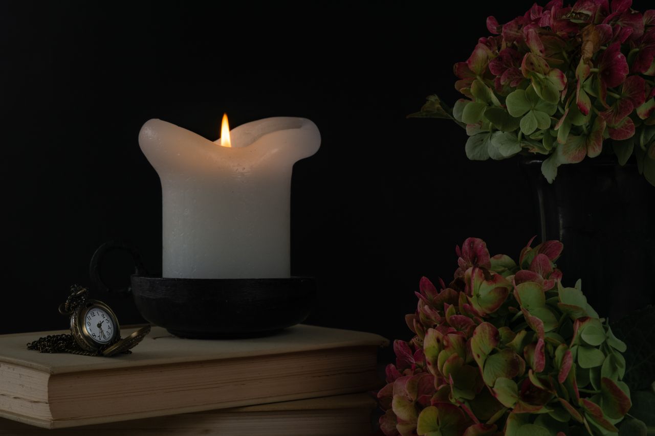 Memorial candle and vintage pocket watch on a book representing remembrance and St. Petersburg, FL cremations traditions