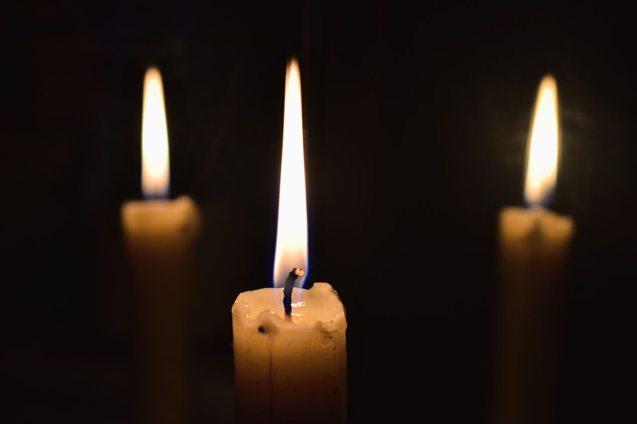 Three lit candles in a dark setting symbolizing remembrance and peaceful St. Petersburg, FL cremations service